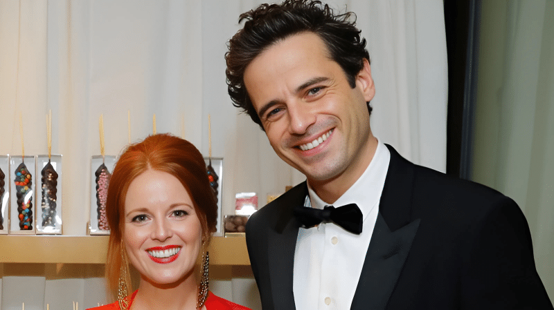 Luke and Andrea dressed in formal attire, with one in a red dress and the other in a black tuxedo, posing at an indoor event.