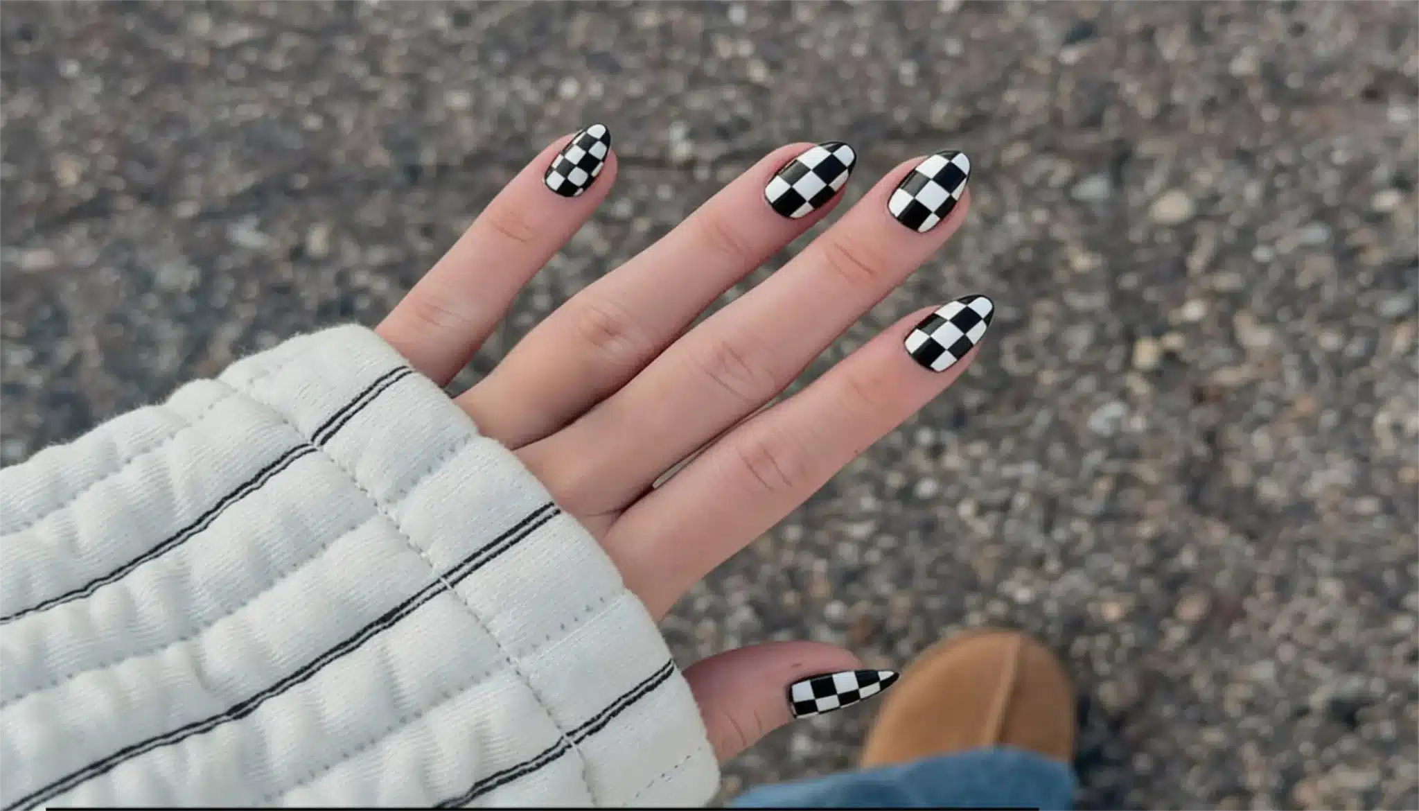 A close-up of a person's hands showcasing black and white checkered nails in a checkerboard pattern showing trendy look