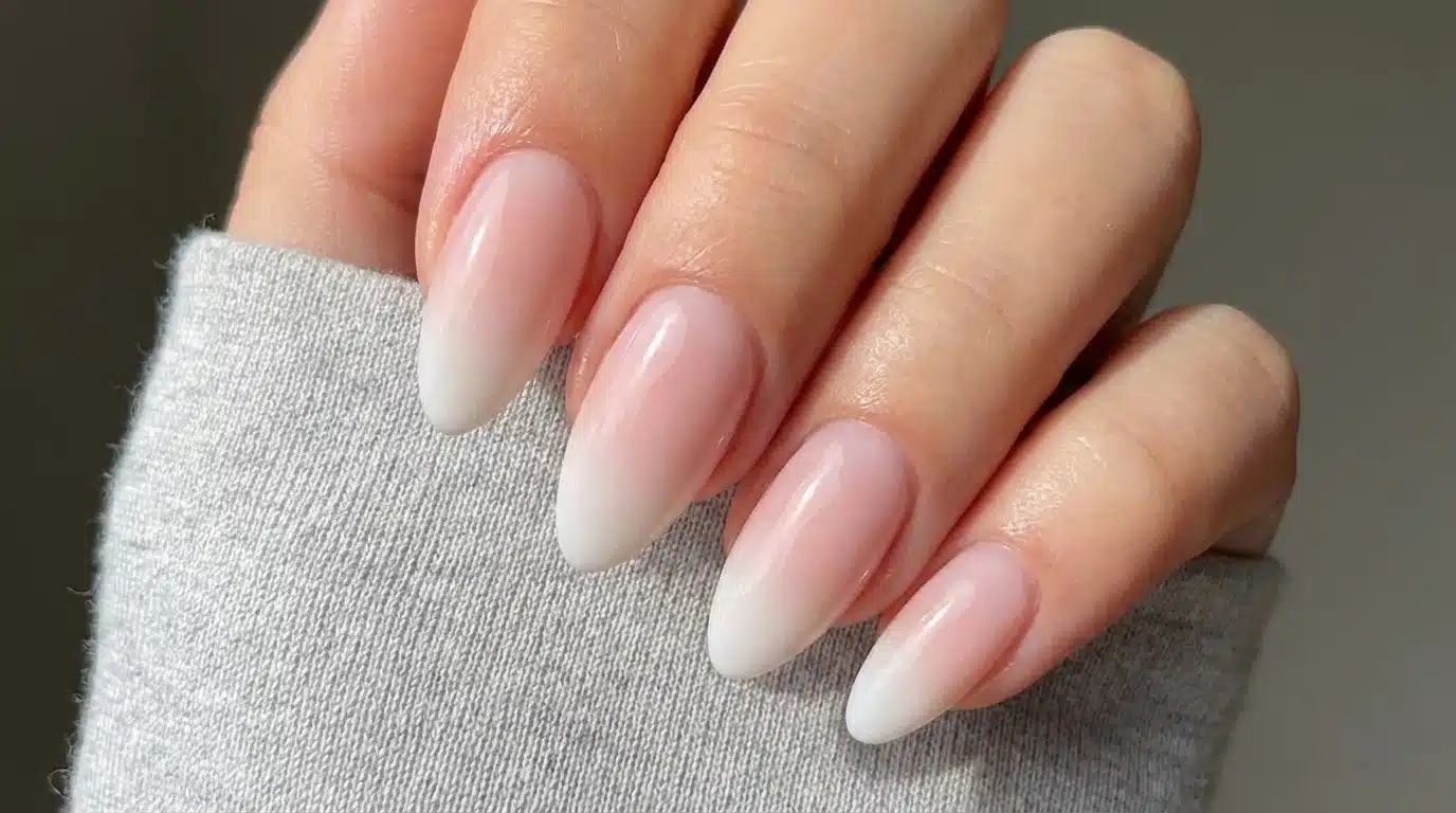 A close-up of a woman's hand showcasing long white dip powder nails