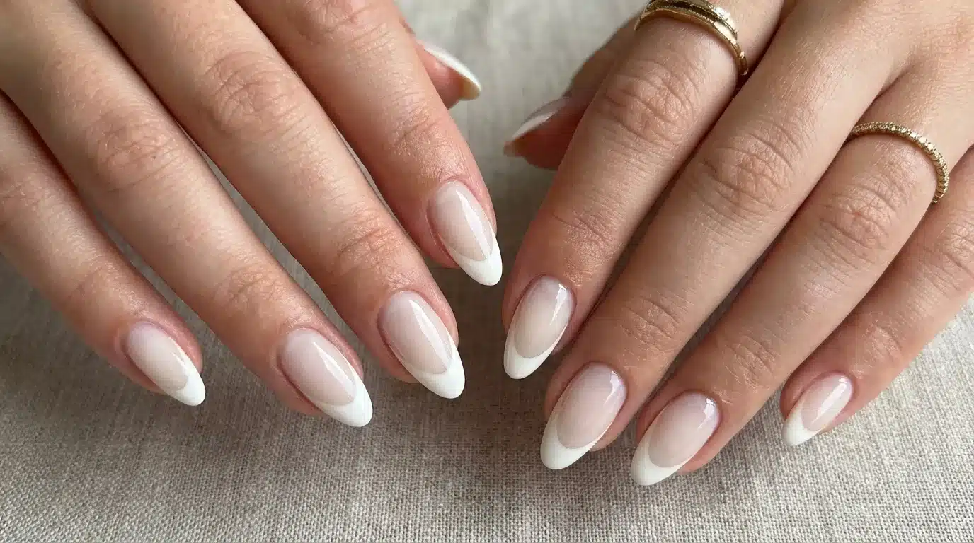 A close-up of a woman's hands showcasing a Deep-Curve French manicure with white and pink nails