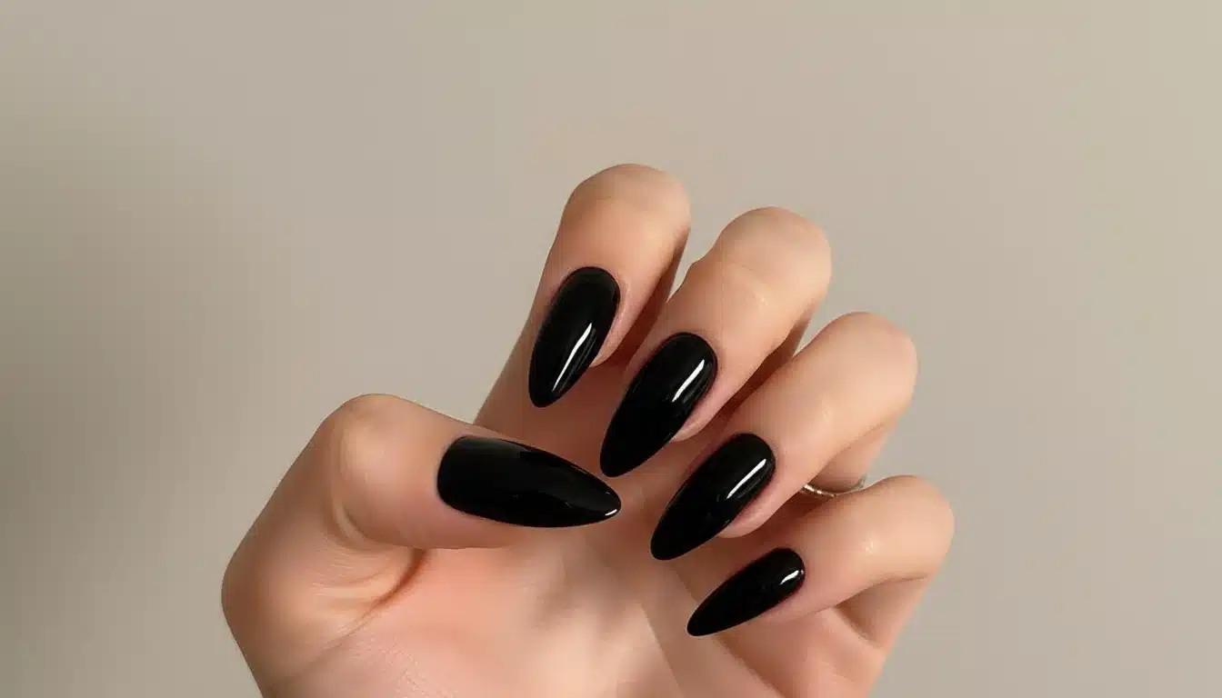A woman's hand showcasing long black almond nails creating a bold and sleek look with a chic oval shape with natural lighting