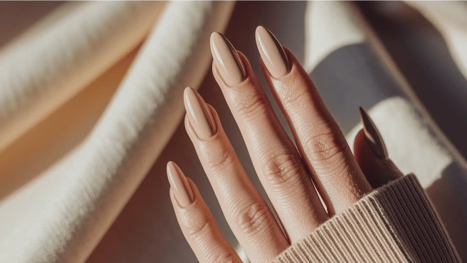 A woman's hands with long manicured nails draped over a soft cream sweater (1)