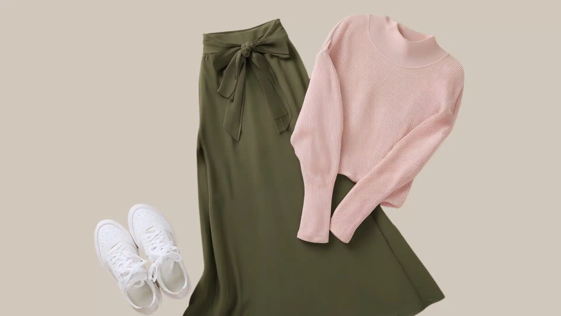 Flat lay of a pink mock neck sweater, an olive green midi skirt with a tie waist, and white lace-up sneakers against a beige background