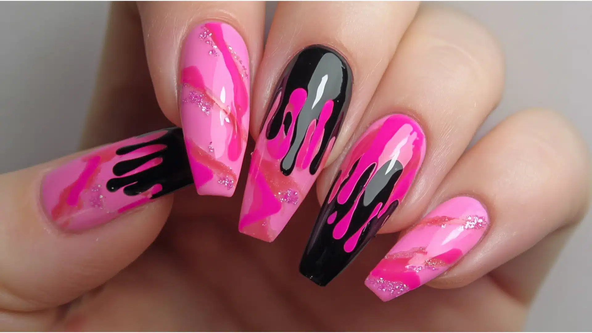 Hot pink drip nail art with glossy black accents, featuring bold melting designs, soft pink base tones, and a sparkly glam finish