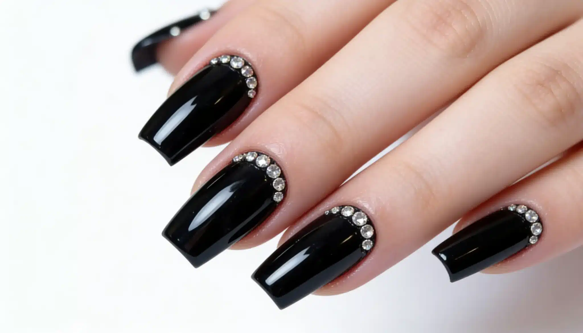 Long glossy black nail polish with silver rhinestones neatly placed on cuticles, creating a stylish and sleek look