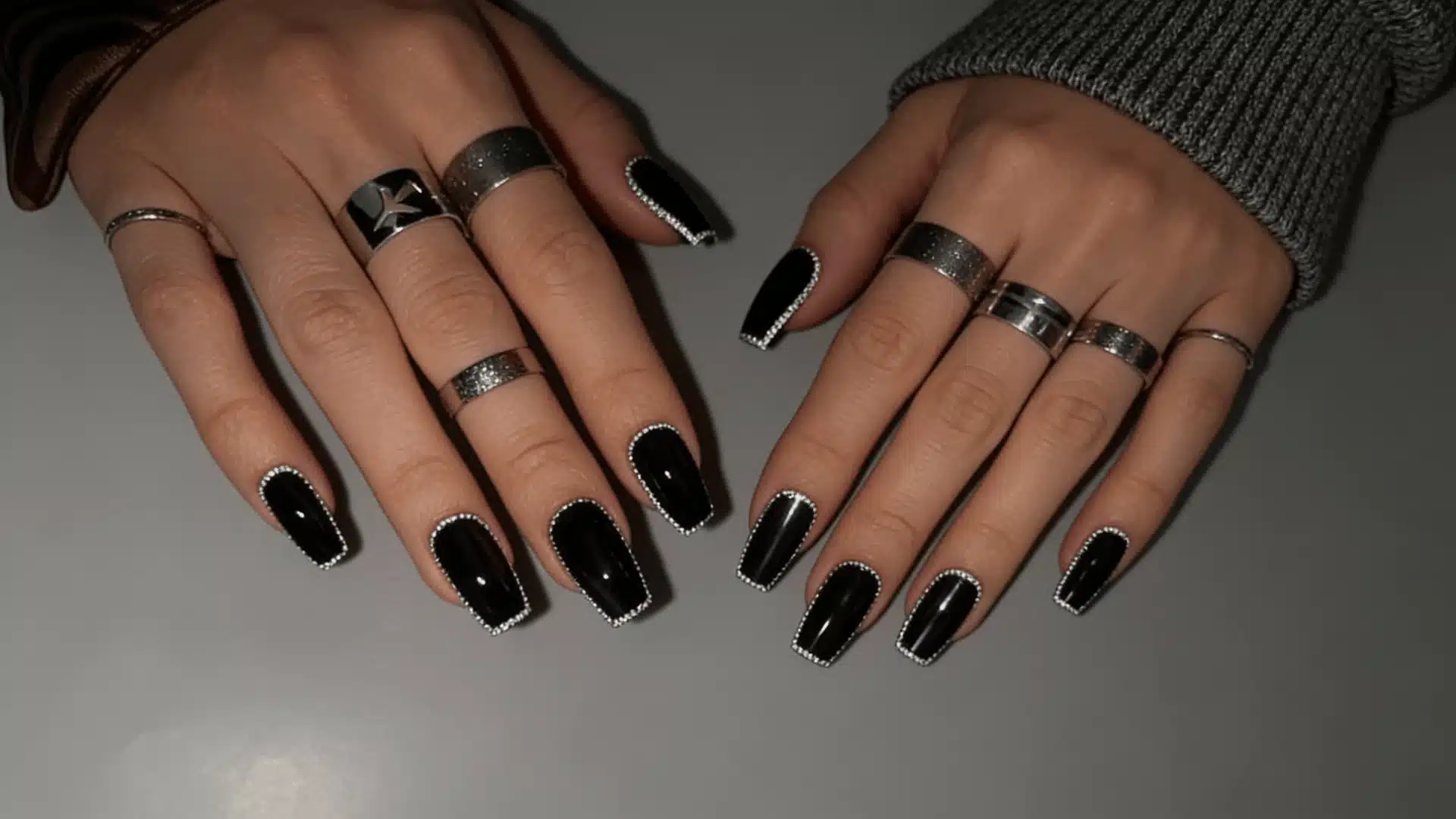 Shiny black nails with silver outlines on all fingers, with silver rings creating a striking monochrome manicure