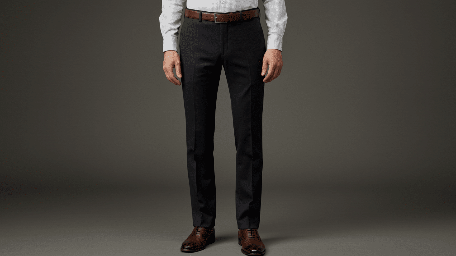 Man in charcoal dress pants with a brown belt, white checkered shirt, and brown leather dress shoes against a dark gray backdrop.