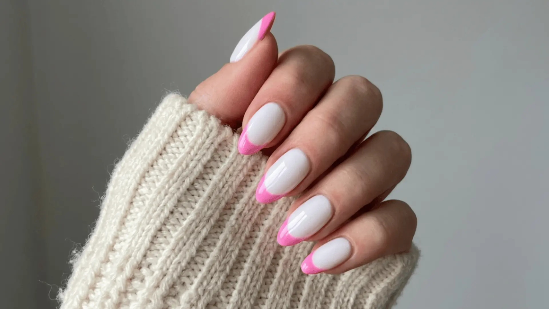 A close-up of a woman's hand with featuring pink white nails with a white base and pink tips creating a fresh and stylish look