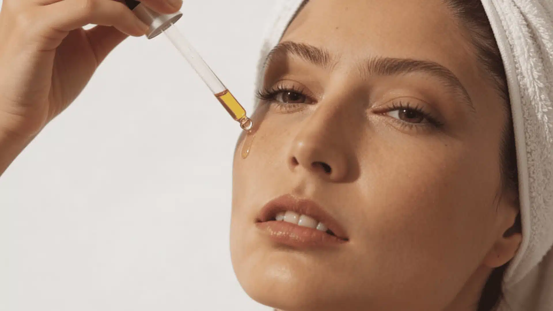 A woman gently applies facial oil to her skin promoting ways show to tighten face skin naturally at home