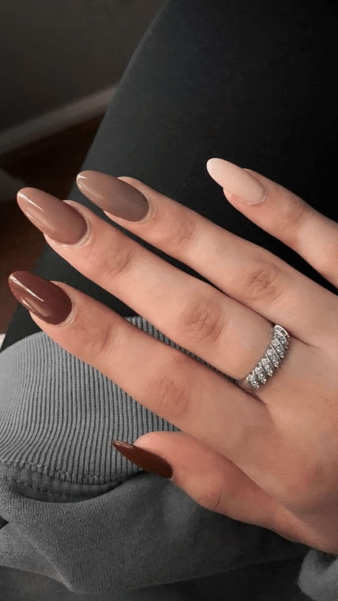 Almond-shaped nails painted in a gradient of brown shades, from dark chocolate to soft nude.