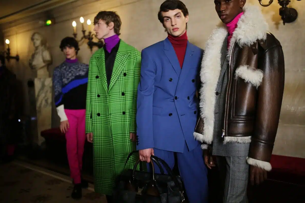 Models showcase Berluti's colorful, patterned outerwear and suits in a dimly lit hallway