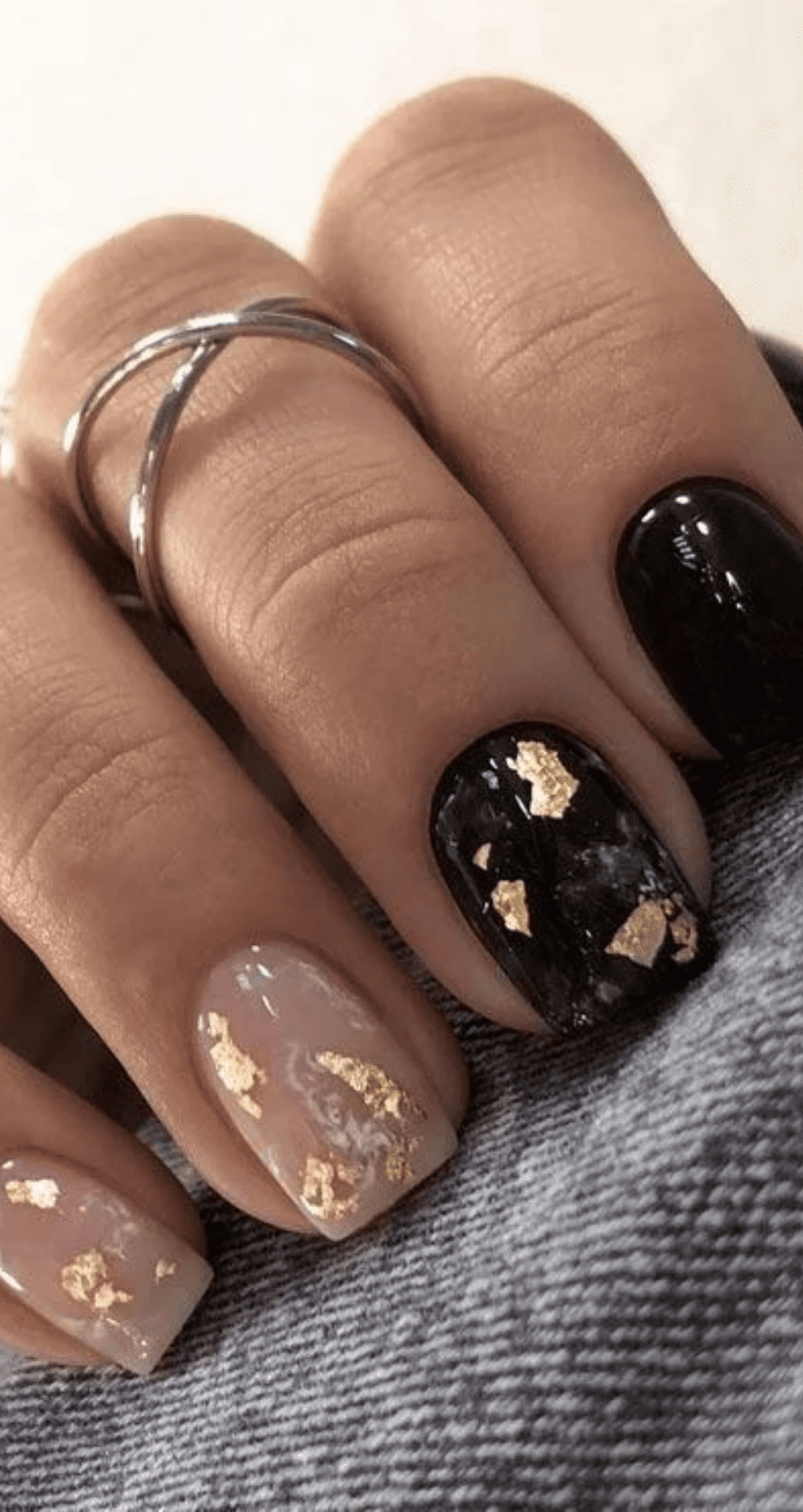 Short square and almond nails with black and nude marbled base accented with gold flakes
