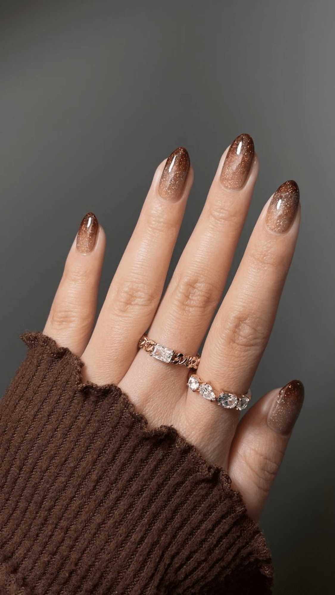 Almond-shaped nails with a glittery brown ombré effect, creating a warm classy brown nail designs look.