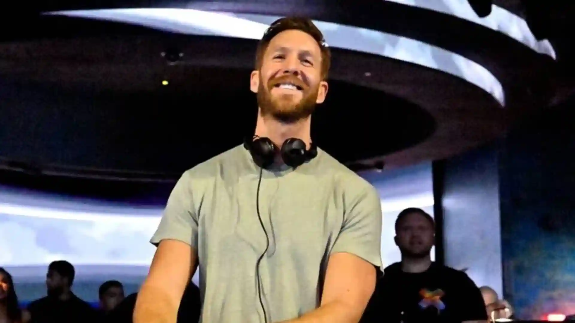 Calvin Harris wearing a headset on a DJ set and playing music.