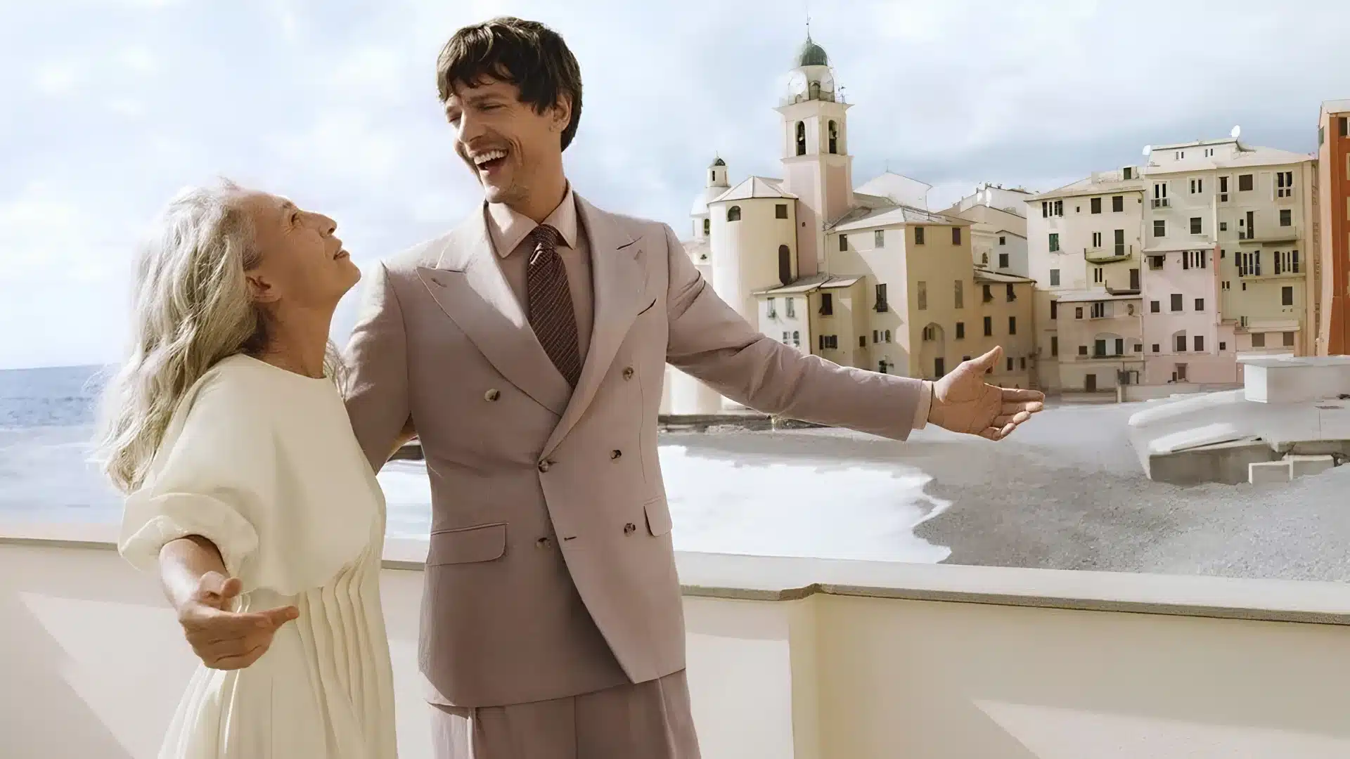 A man in a light brown Canali's suit and a woman stand on a balcony