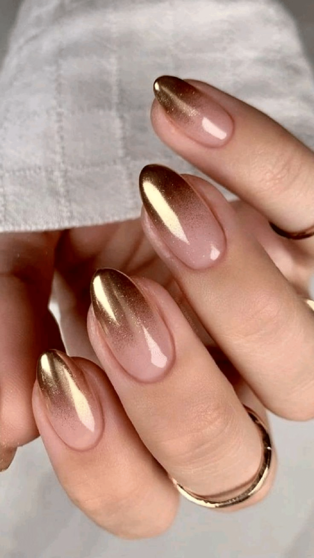 Glossy almond nails with a soft nude base fading into metallic gold tips, a stunning and classy brown nail designs look.