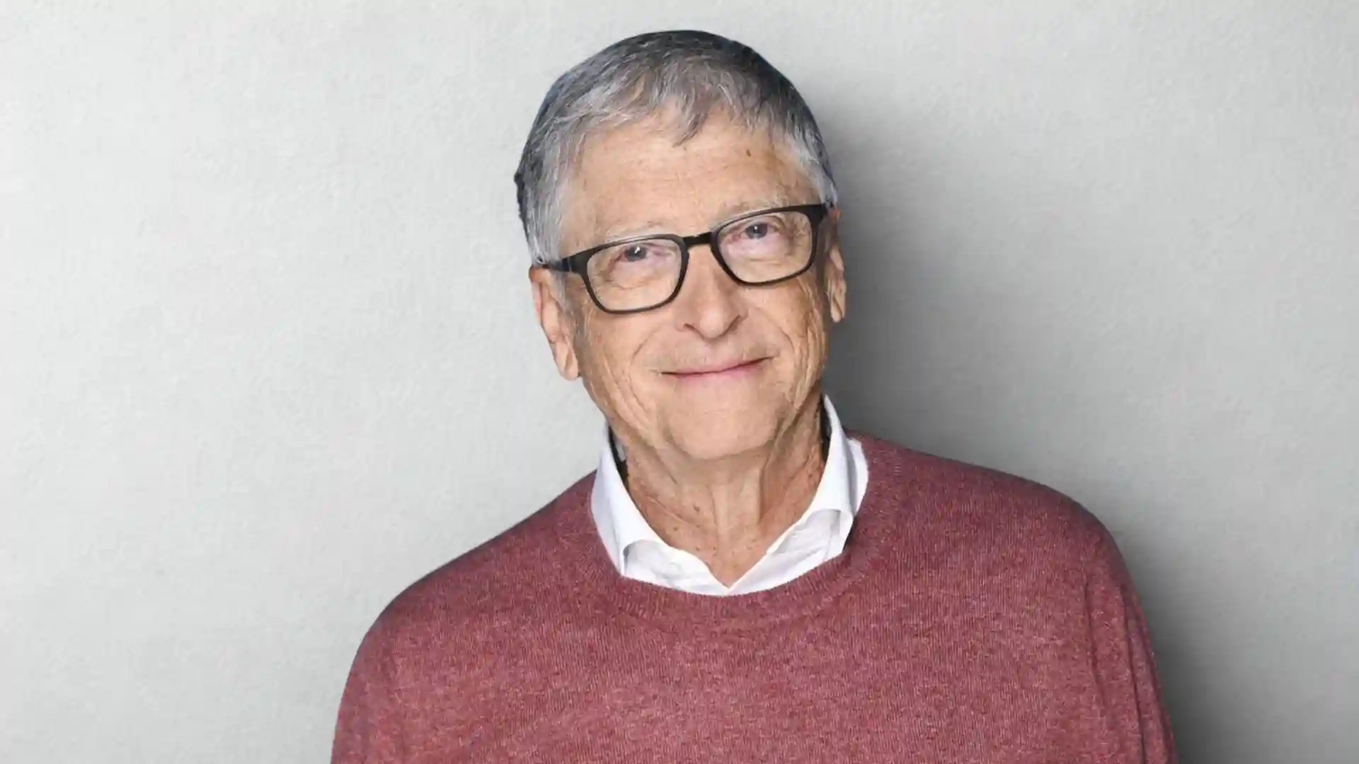 Smiling portrait of Bill Gates wearing glasses and a maroon sweater.