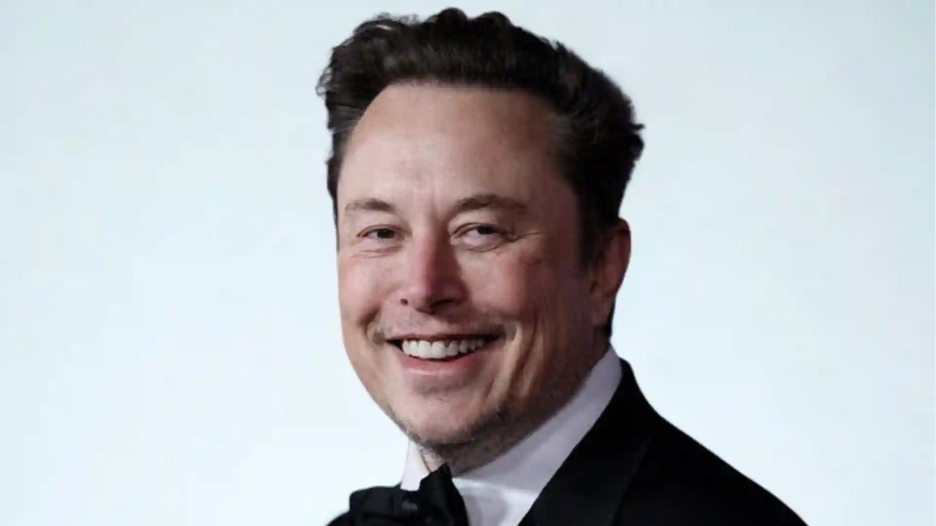 Elon Musk smiles wearing a tuxedo and bow tie.