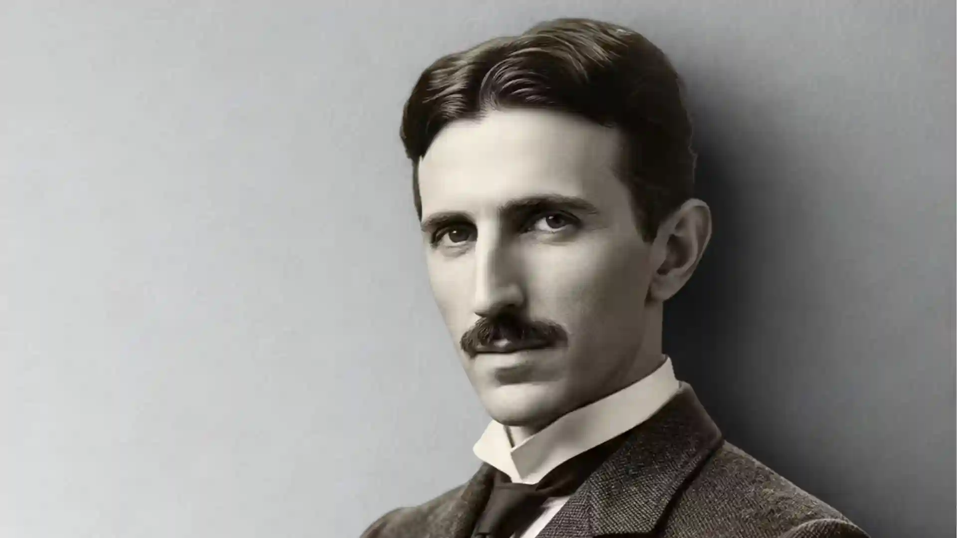 Portrait of Nikola Tesla in a suit and tie with a prominent mustache.