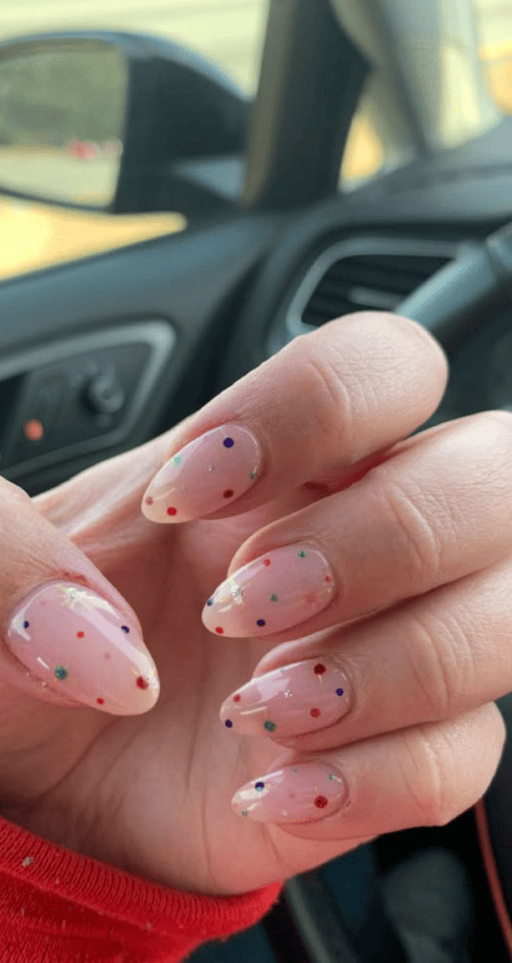 Almond shaped nails with clear pink base covered in small colorful dots on all nails