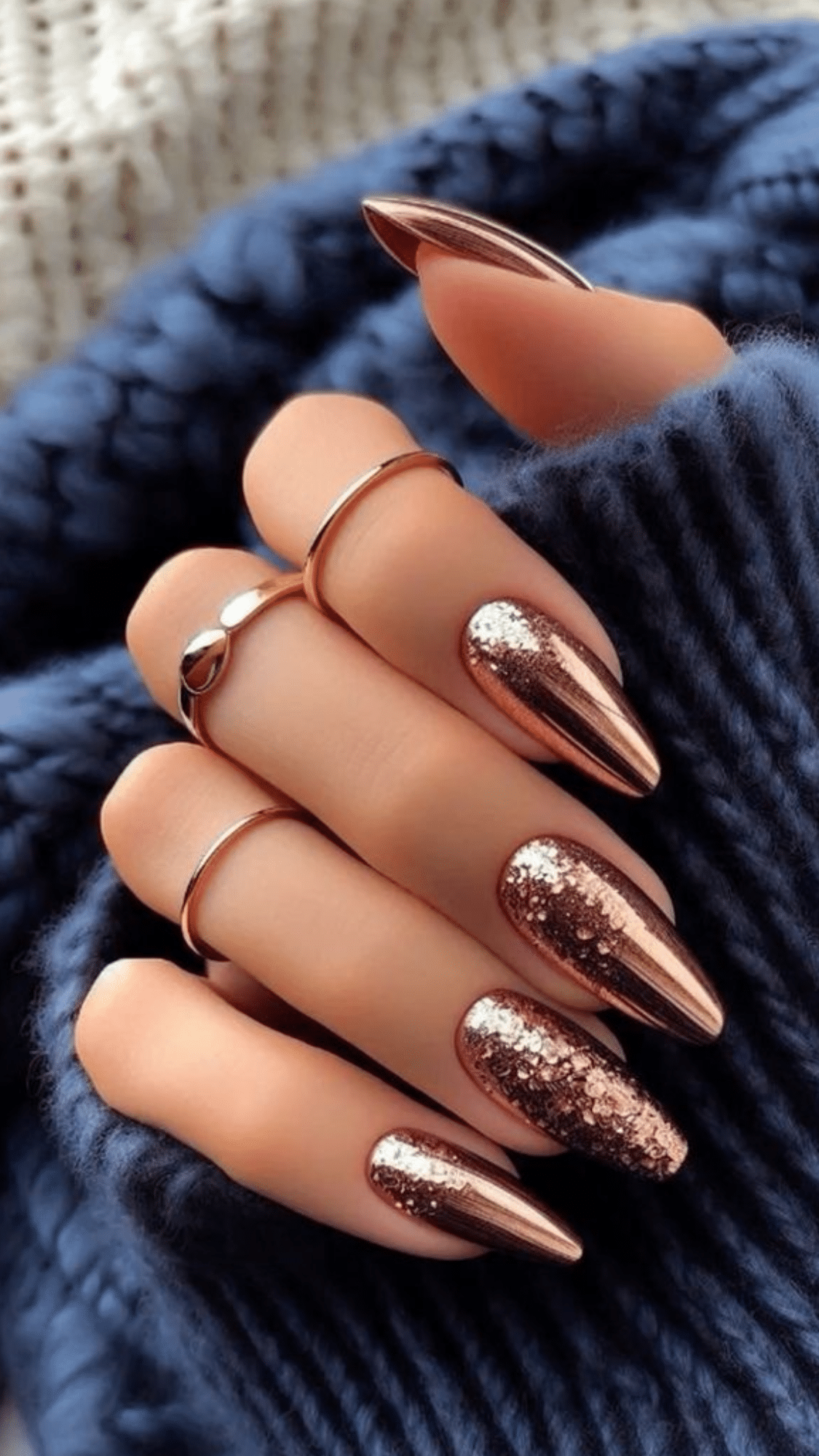 Almond-shaped nails with a metallic rose gold finish and glitter accents