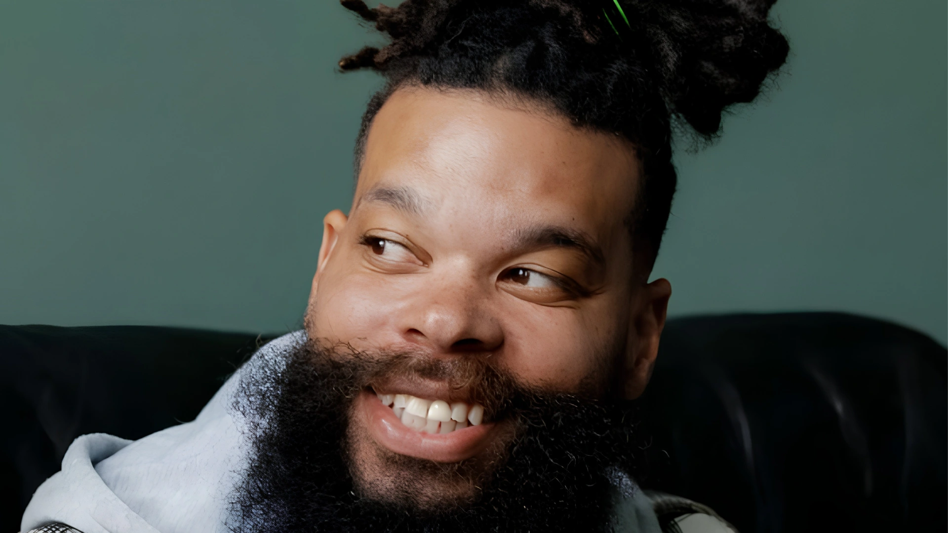 Close up of Damon Darling smiling and looking to the side against a teal background