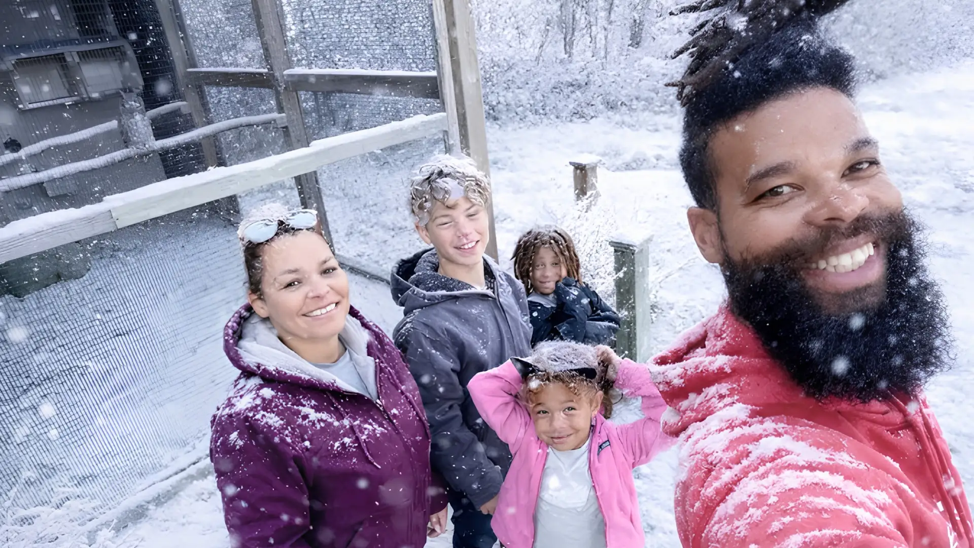 Damon Darling's family of five smiling and posing for a selfie in a snowy outdoor enclosure