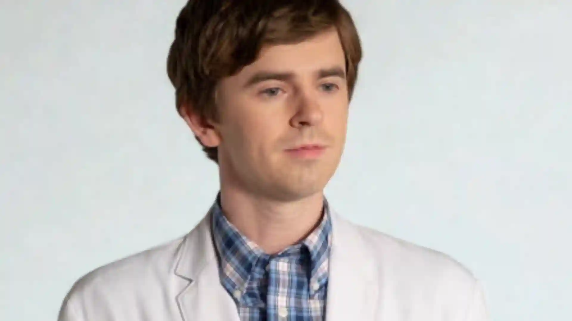 Portrait of Dr. Shaun Murphy (Freddie Highmore) from The Good Doctor, in a white lab coat.