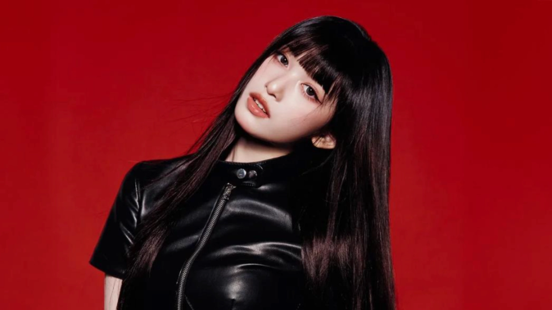 Gaeul with long black hair wearing a stylish leather jacket, posing confidently against a neutral background.