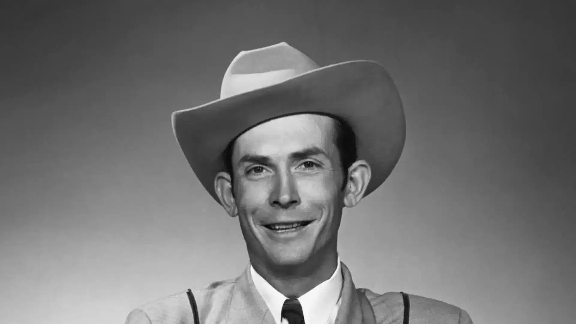 Black and white headshot of Hank Williams wearing a cowboy hat and suit
