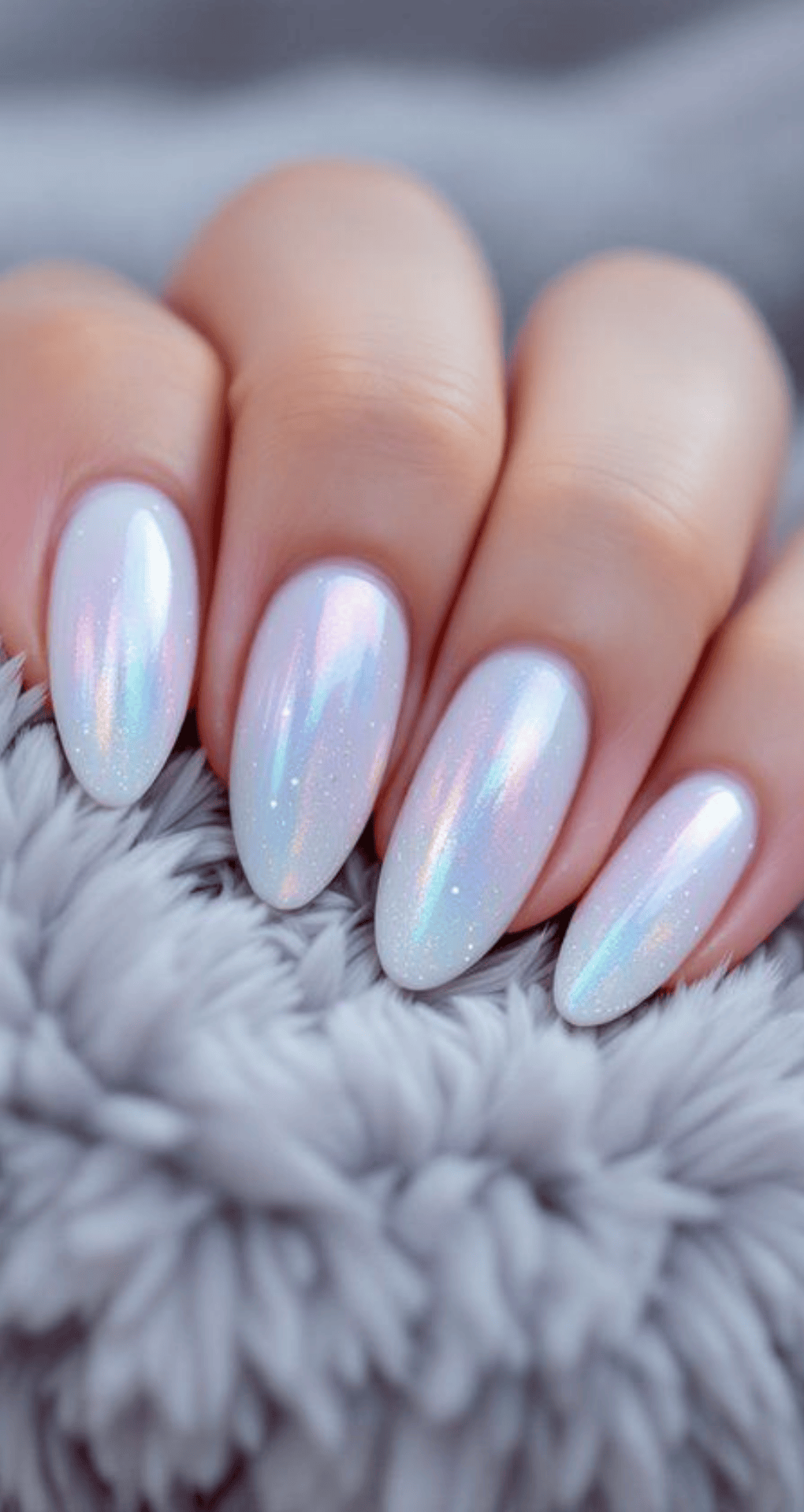 Almond nails with pearlescent white base reflecting rainbow colors with subtle shimmer throughout