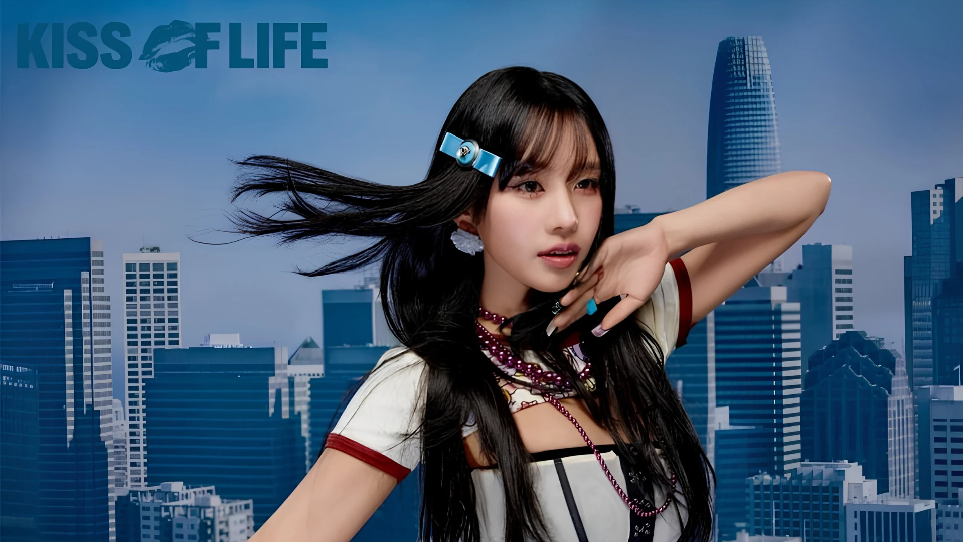 Kiss of Life member Natty with with black hair and a white shirt against a backdrop of city skyscrapers