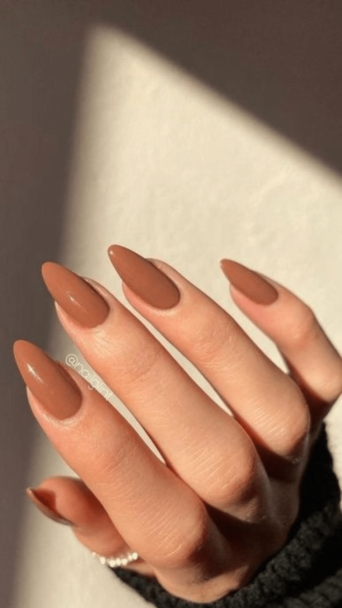 Almond-shaped nails painted in a warm caramel brown shade