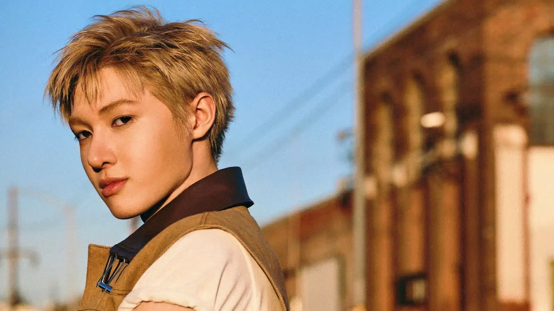 Martin featuring blond textured hair, a stylish layered outfit, and a confident pose in warm outdoor lighting.