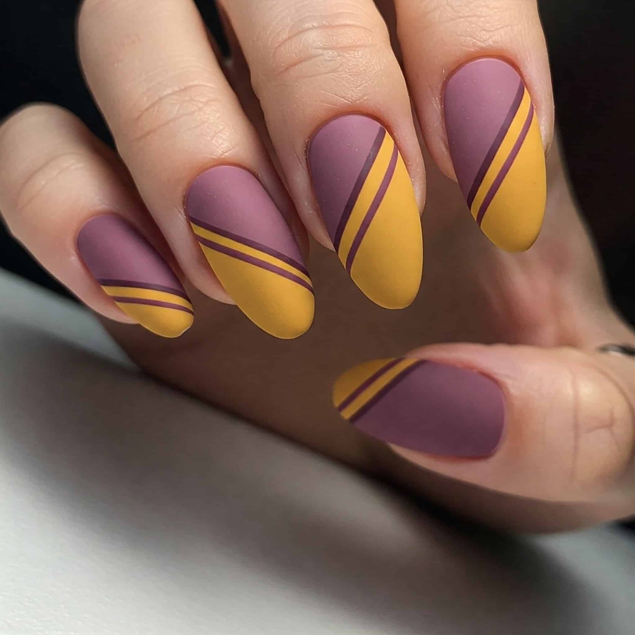 A close-up of a woman's hand showcasing a vibrant purple and yellow manicure