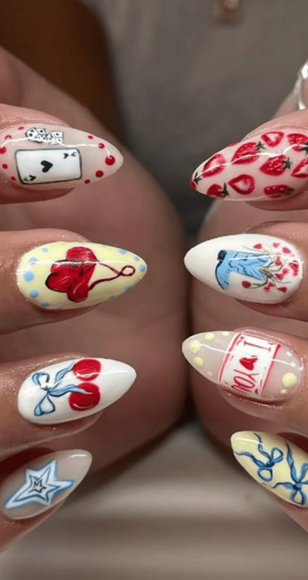 Pointed nails with different base colors featuring detailed small art of hearts cherries and stars