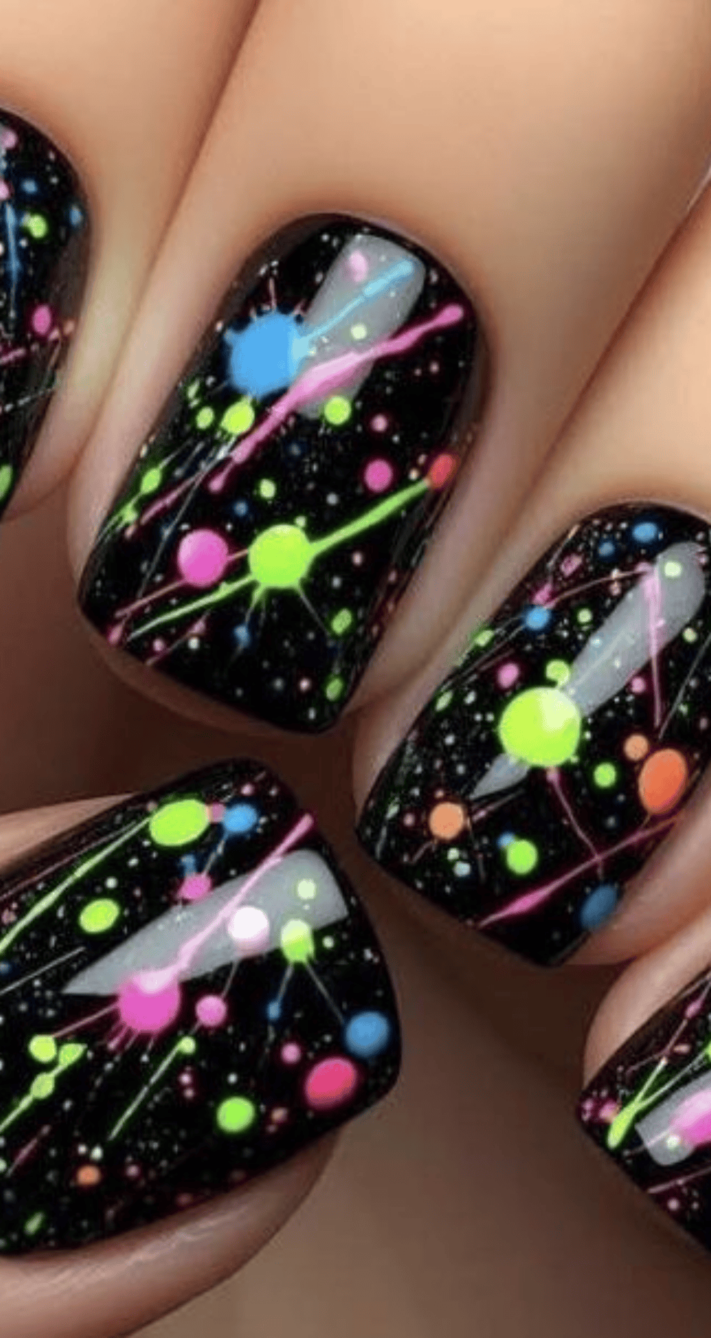 Short square nails with black base and neon paint splatters in pink blue green and yellow