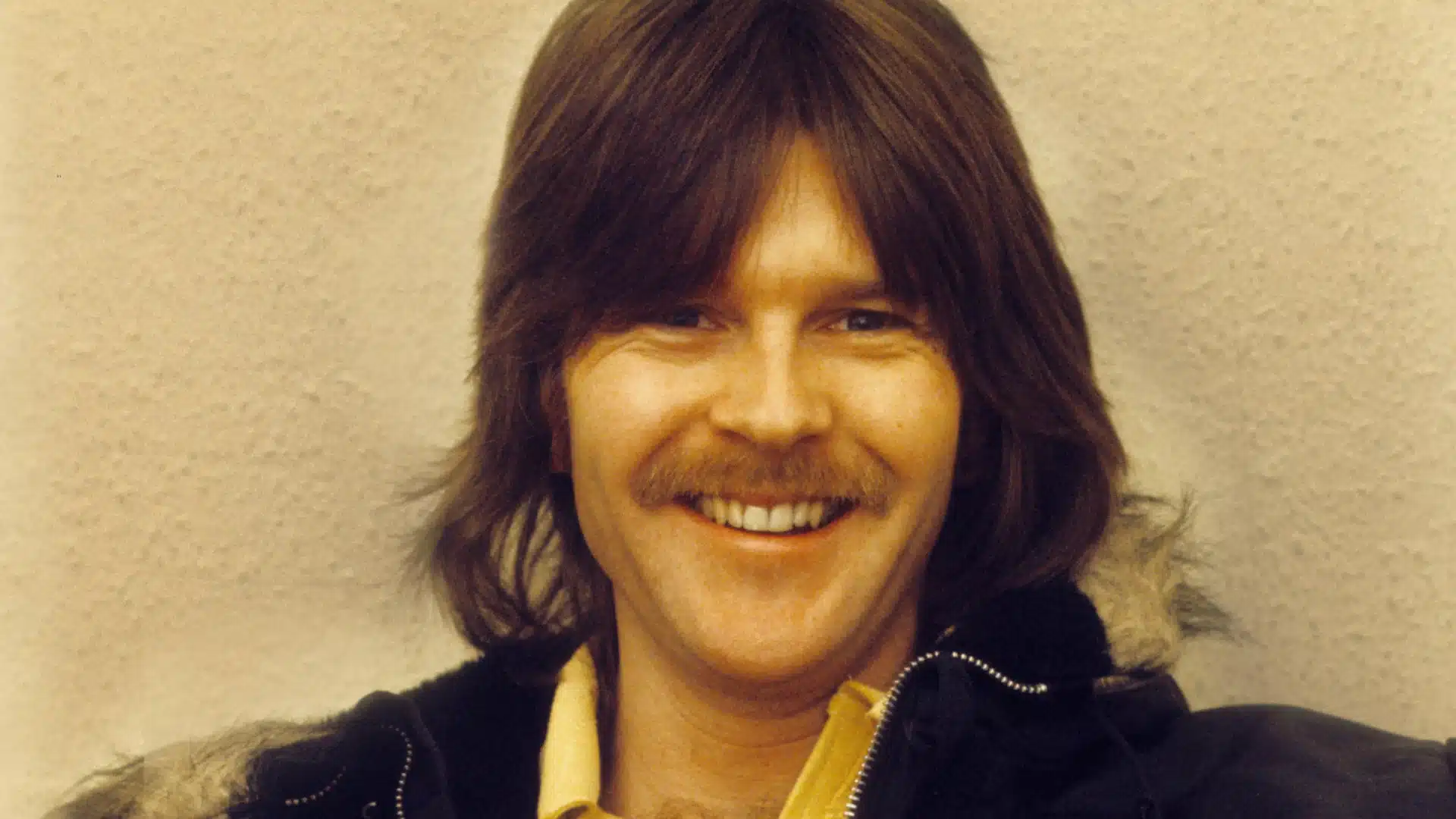 Randy Meisner wearing a yellow shirt and a dark, fur lined jacket