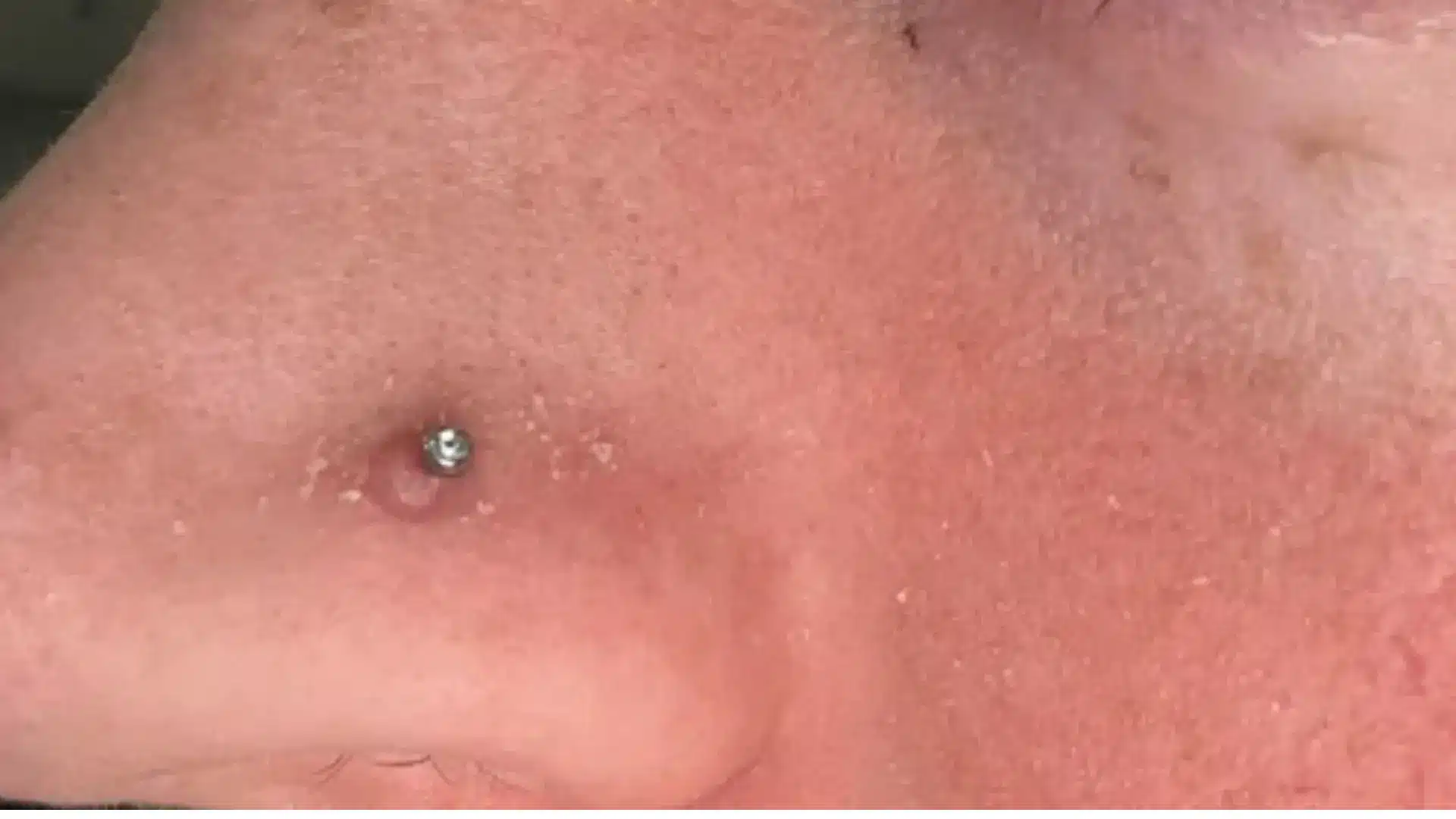 Close-up of a person's nose with a silver stud nose ring piercing.