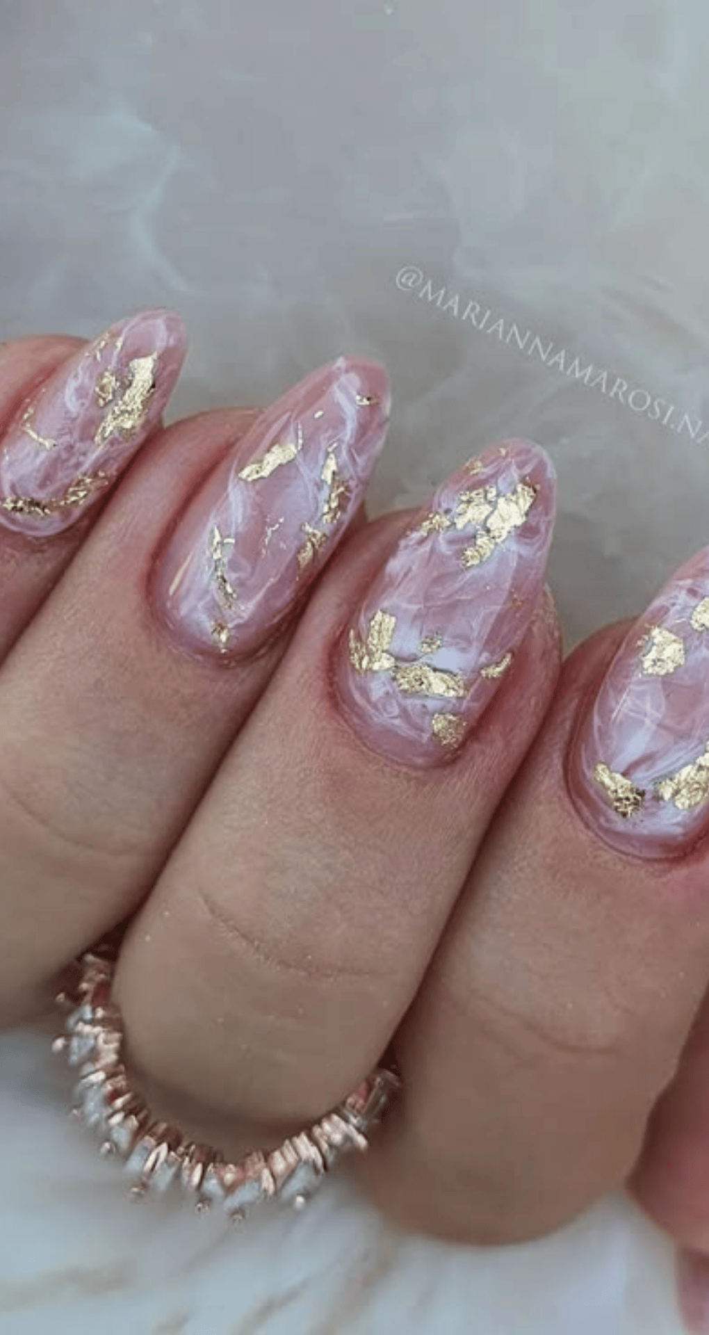Almond nails with pink marble base accented with scattered metallic gold flakes throughout nails