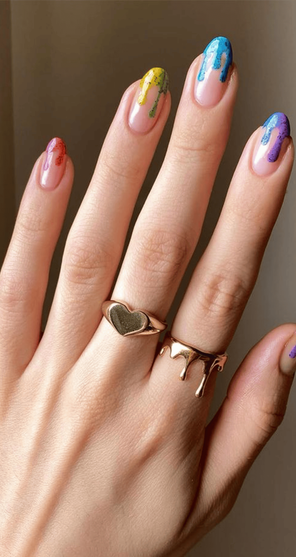 Almond nails with nude base and tips featuring dripping colors in red yellow green blue and purple