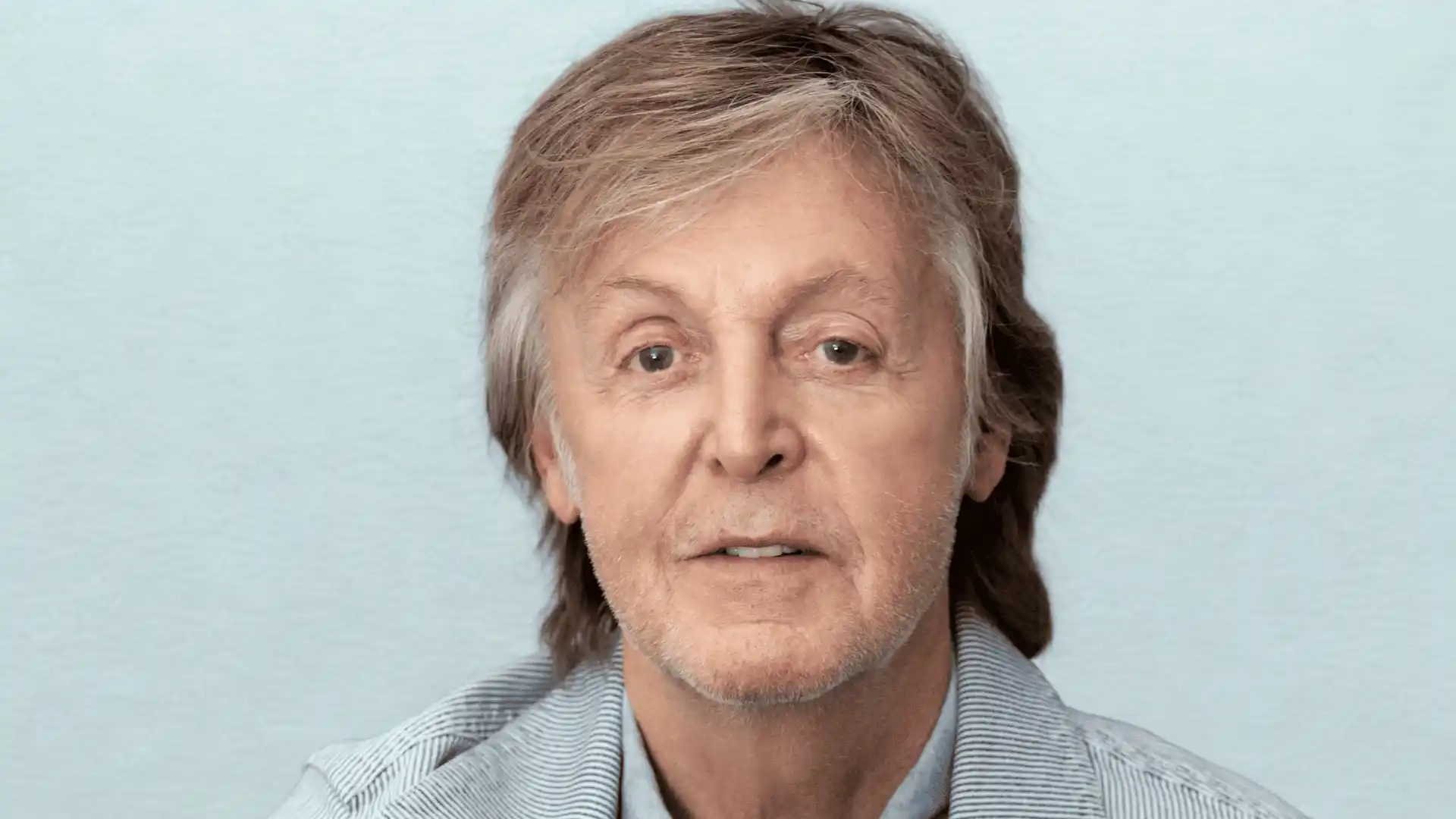 Portrait of Paul McCartney with grey hair, looking forward against a light background.