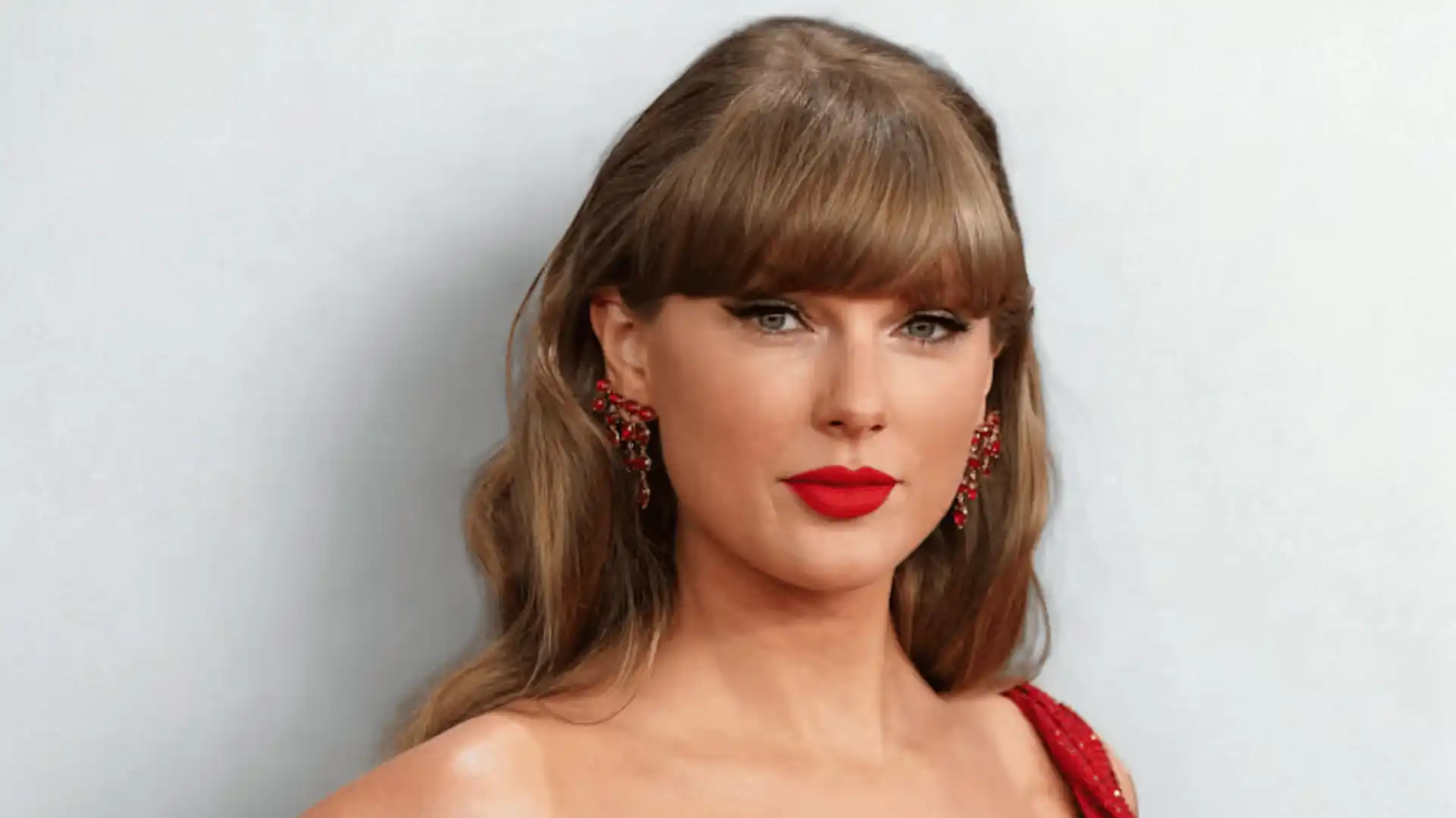 Taylor Swift in a red dress with dramatic red earrings and red lipstick.