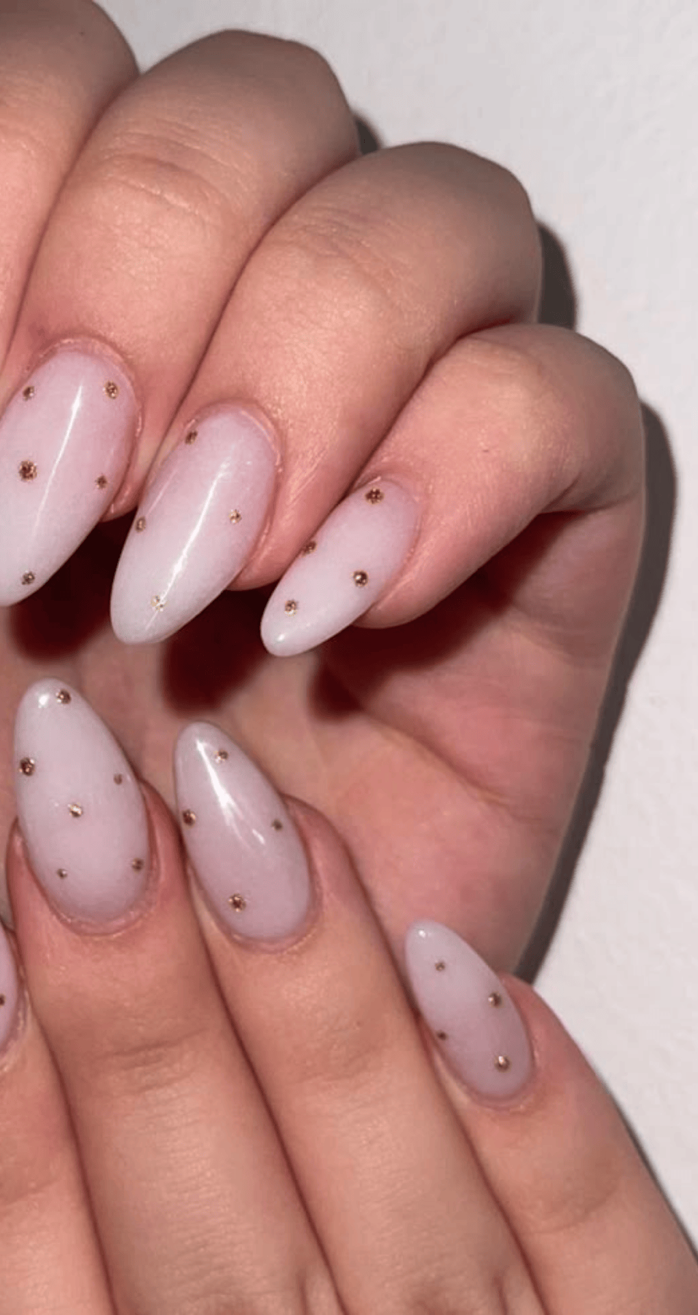 Pointed nails with pale pink base and small evenly spaced metallic gold dots on all nails