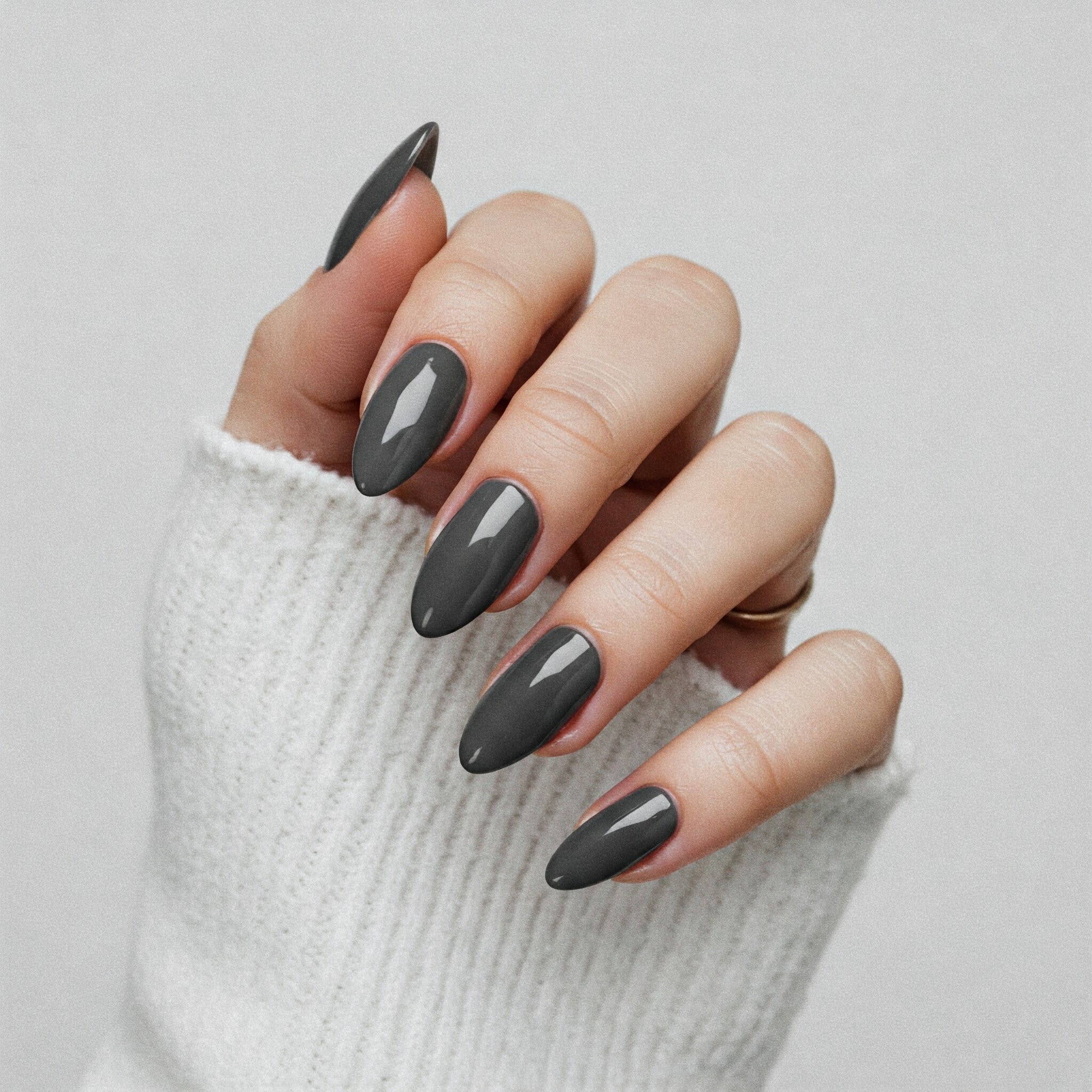 A close-up of a woman's hand grasping a gray nail, showcasing her manicured fingers