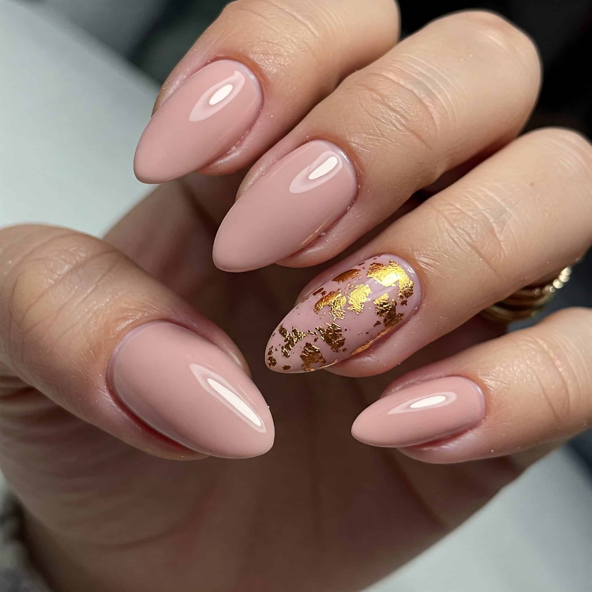 Close-up of a hand with almond-shaped nails painted in glossy nude polish.