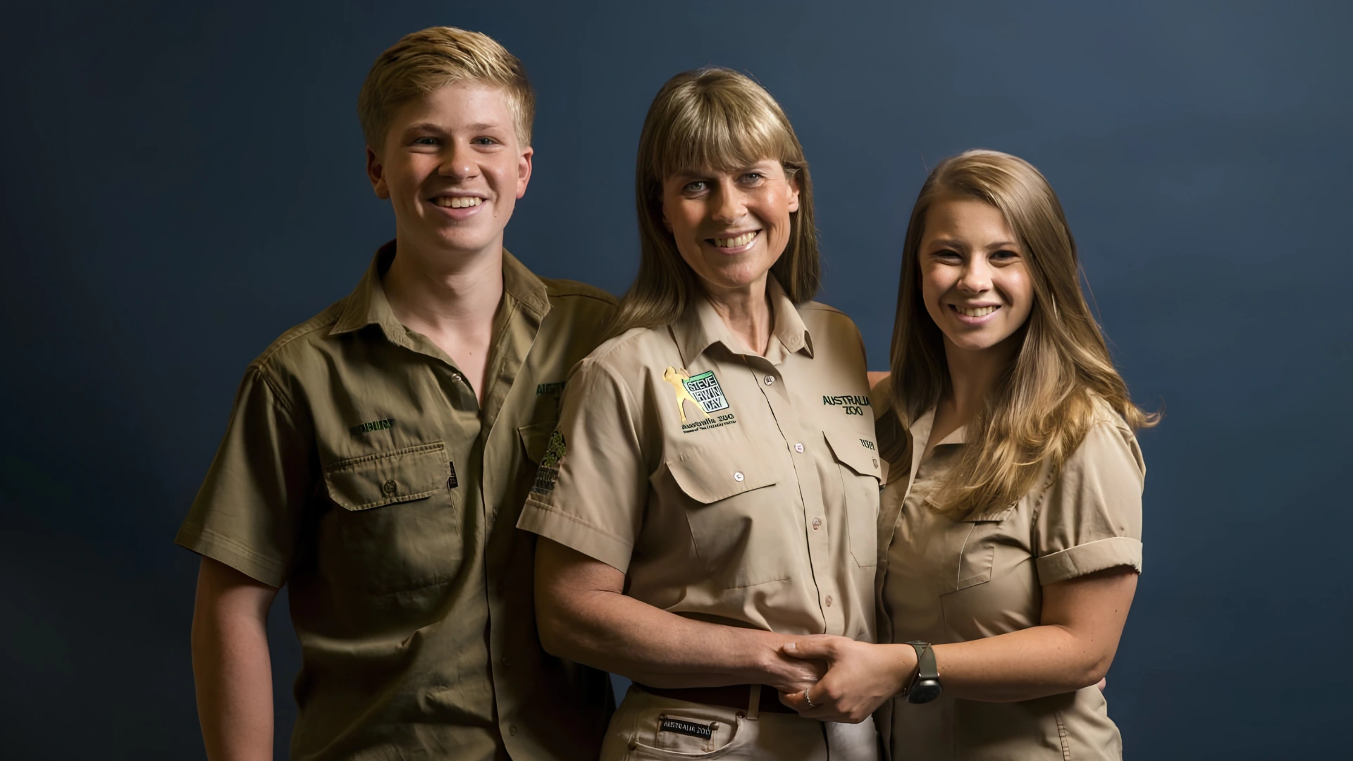 Terri Irwin stands with her children Robert and Bindi Irwin, all wearing khaki Australia Zoo uniforms