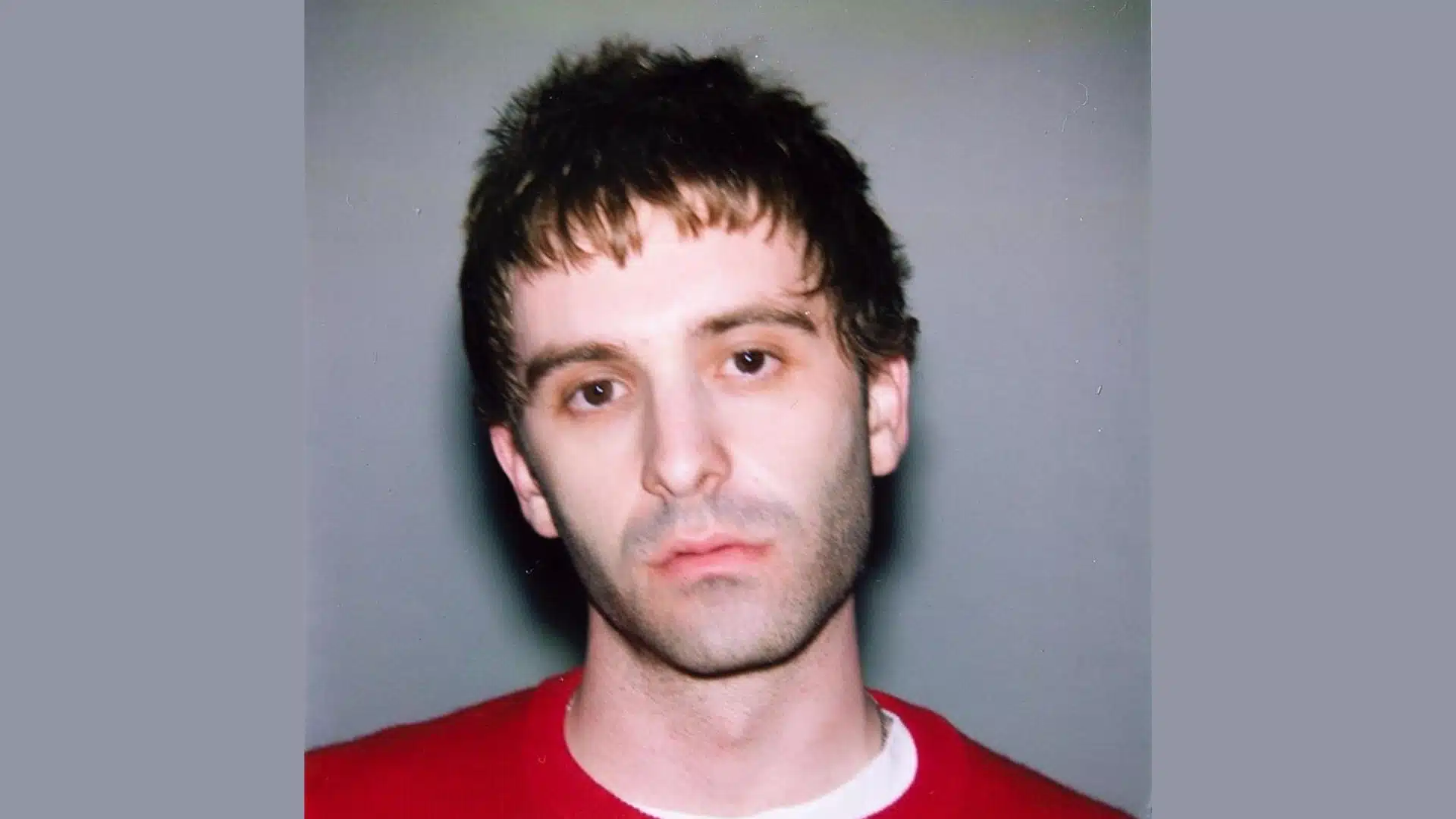 Close up portrait of Jesse Perlman with short, dark, messy hair and a red sweater
