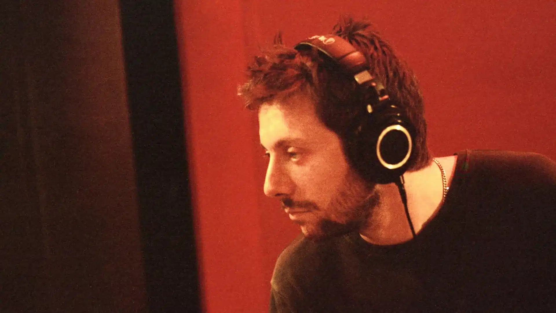 Josh Conway wearing headphones and a black shirt with a red background