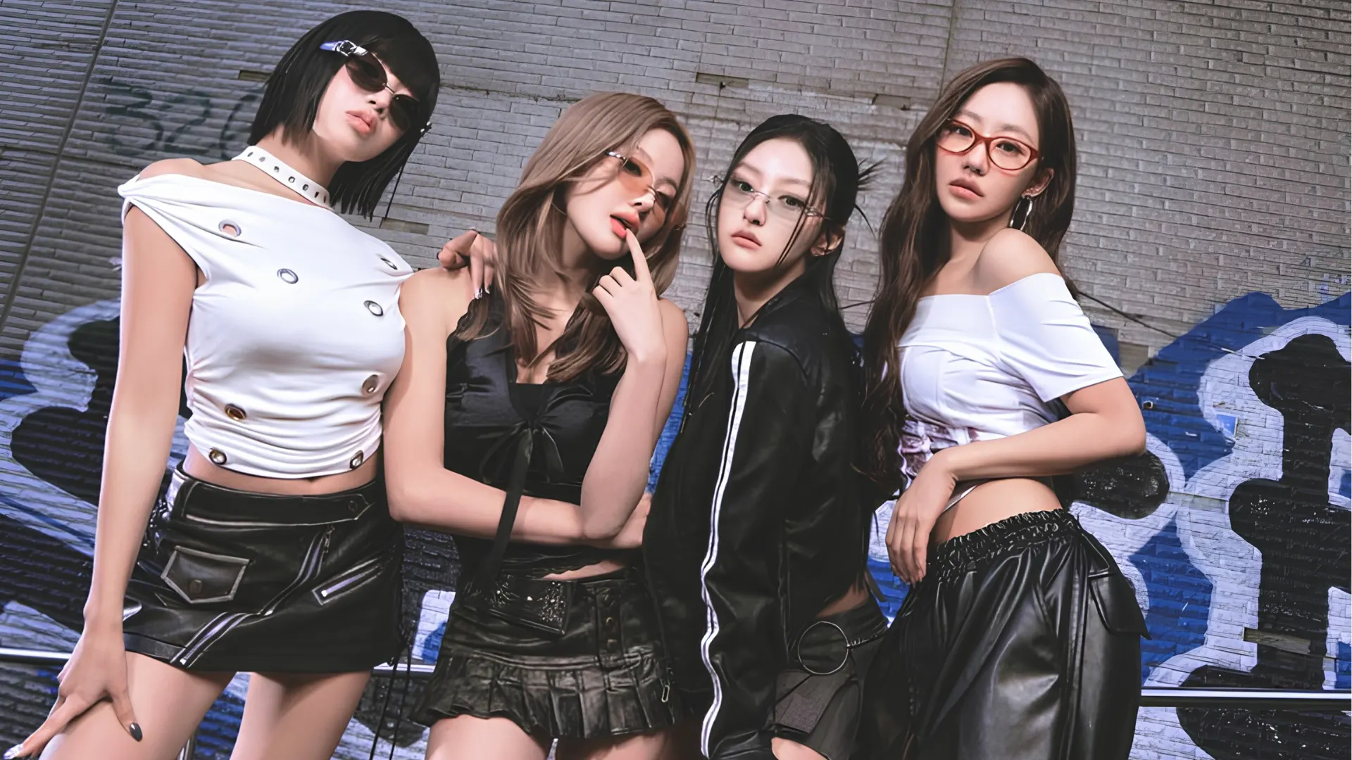 Kiss of Life members in stylish streetwear pose against a graffiti covered brick wall